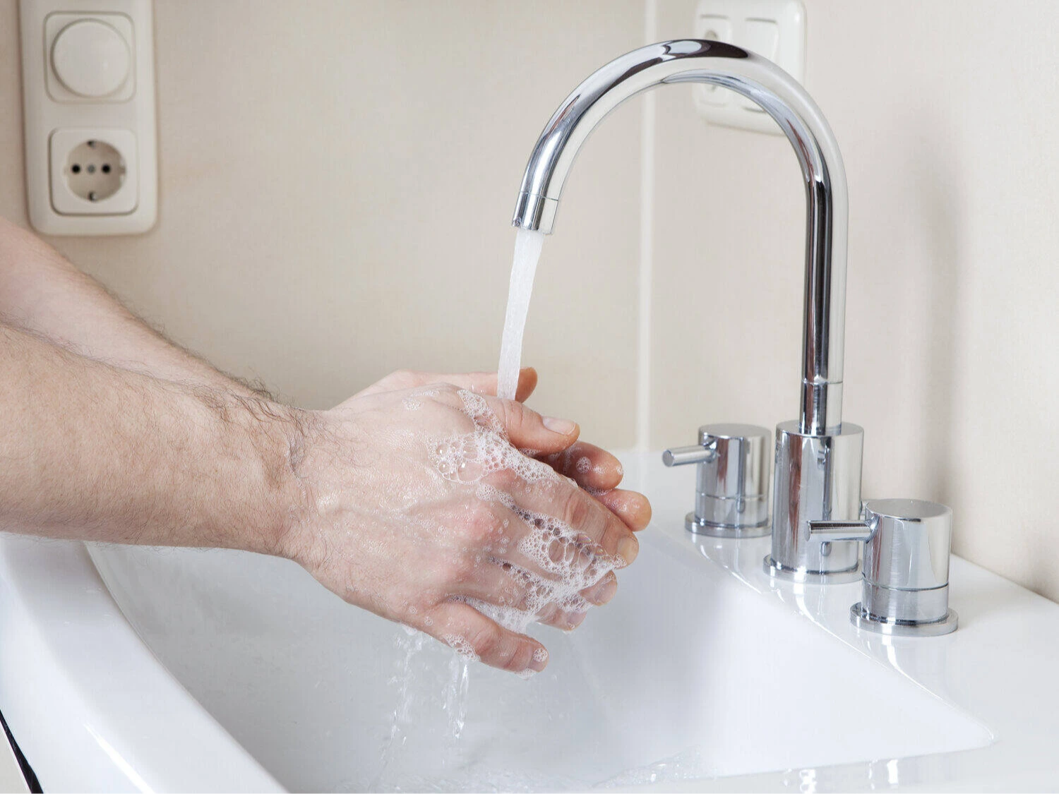 Hände waschen mit Seife unter Wasserhahn am Waschbecken, Hygiene im Bad